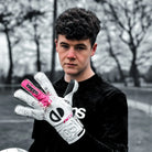 Person wearing a black shirt and white gloves with pink accents, standing outdoors.